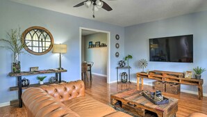 A living room with a leather sofa, a wooden coffee table, a TV, and a ceiling fan.