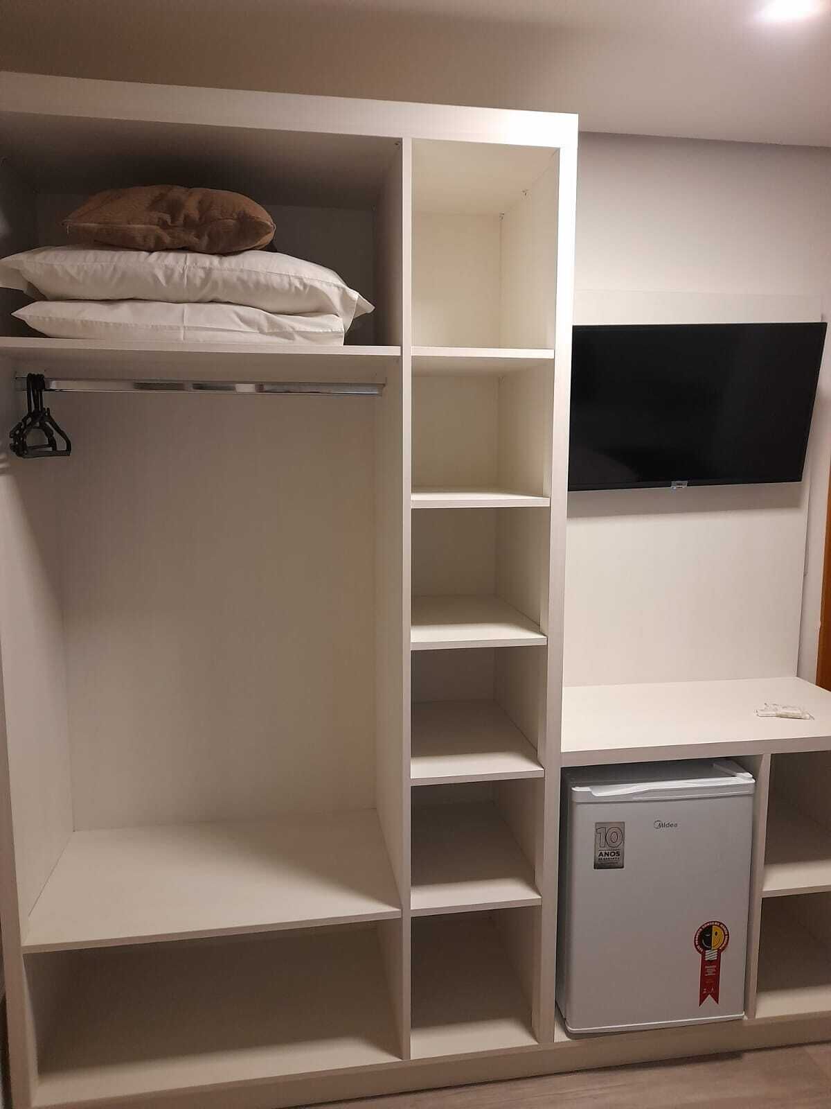 Une chambre avec un lit, une armoire, une télévision et un mini-réfrigérateur.