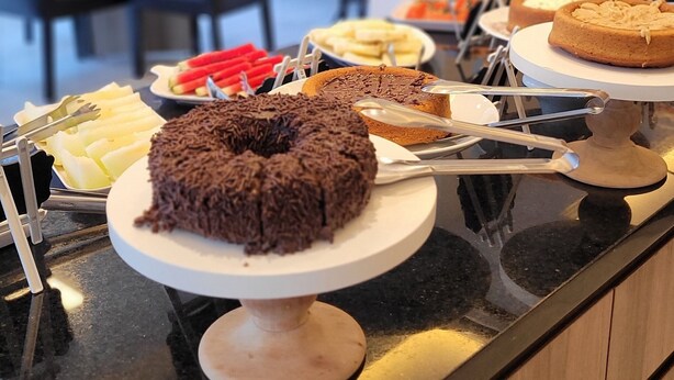 A buffet counter with various desserts and a seating area in the background.