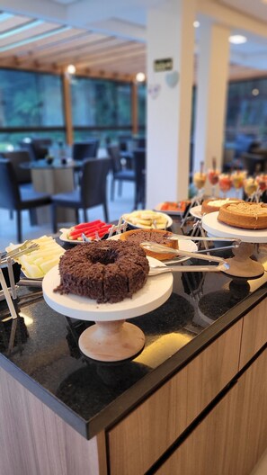 Mostrador de buffet con diversos postres y una zona de estar al fondo.