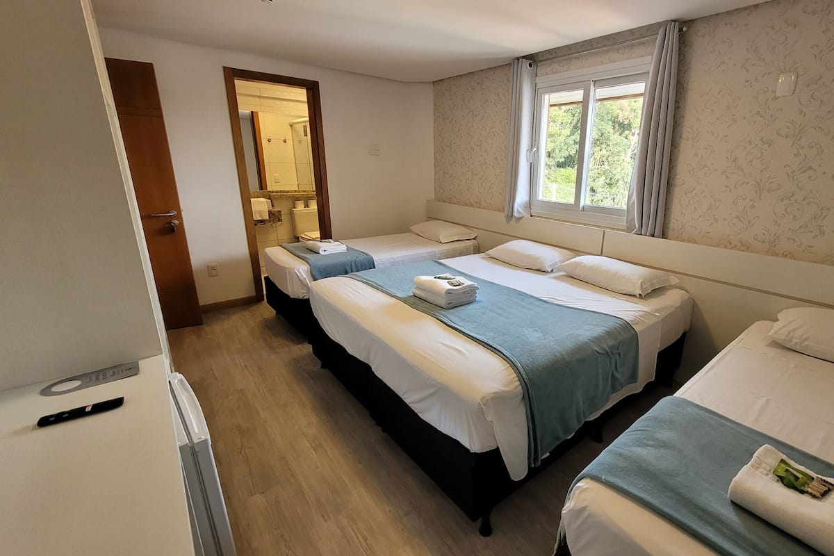 A hotel room with two beds, a bathroom, and a window with curtains.