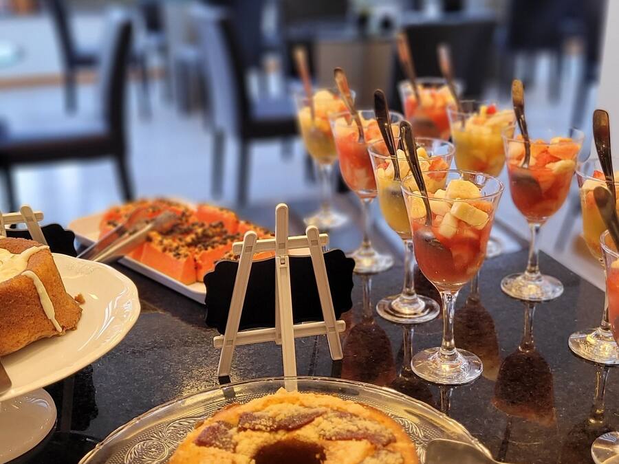 A buffet table with various desserts and drinks, including a bundt cake and fruit parfaits.