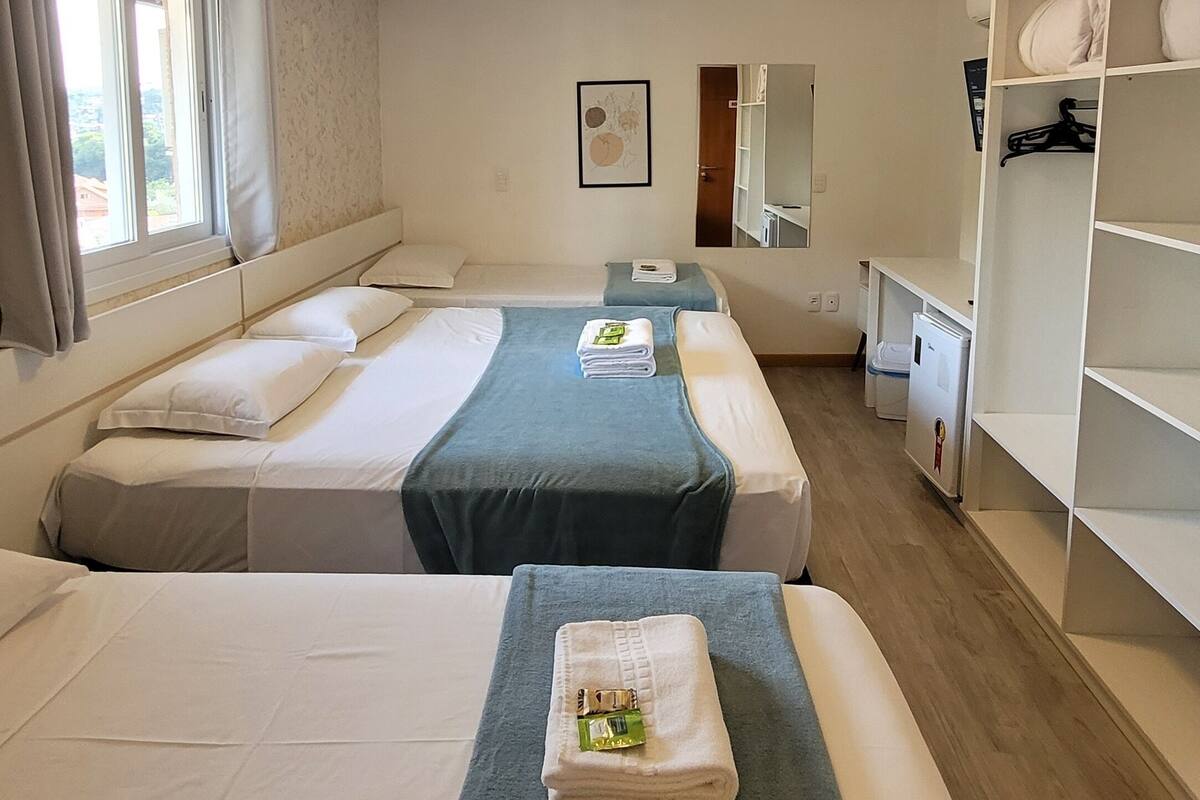 A hotel room with two beds, a wardrobe, a desk, and a mirror.
