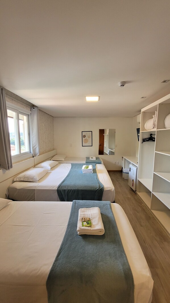 Una habitación de hotel con dos camas, un armario, un escritorio y un espejo.