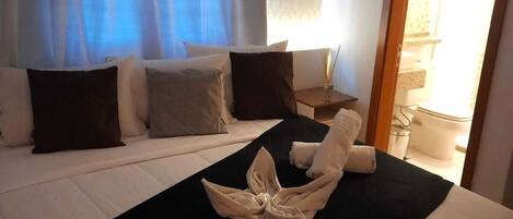 A hotel room with a bed, a nightstand, and a window with curtains.