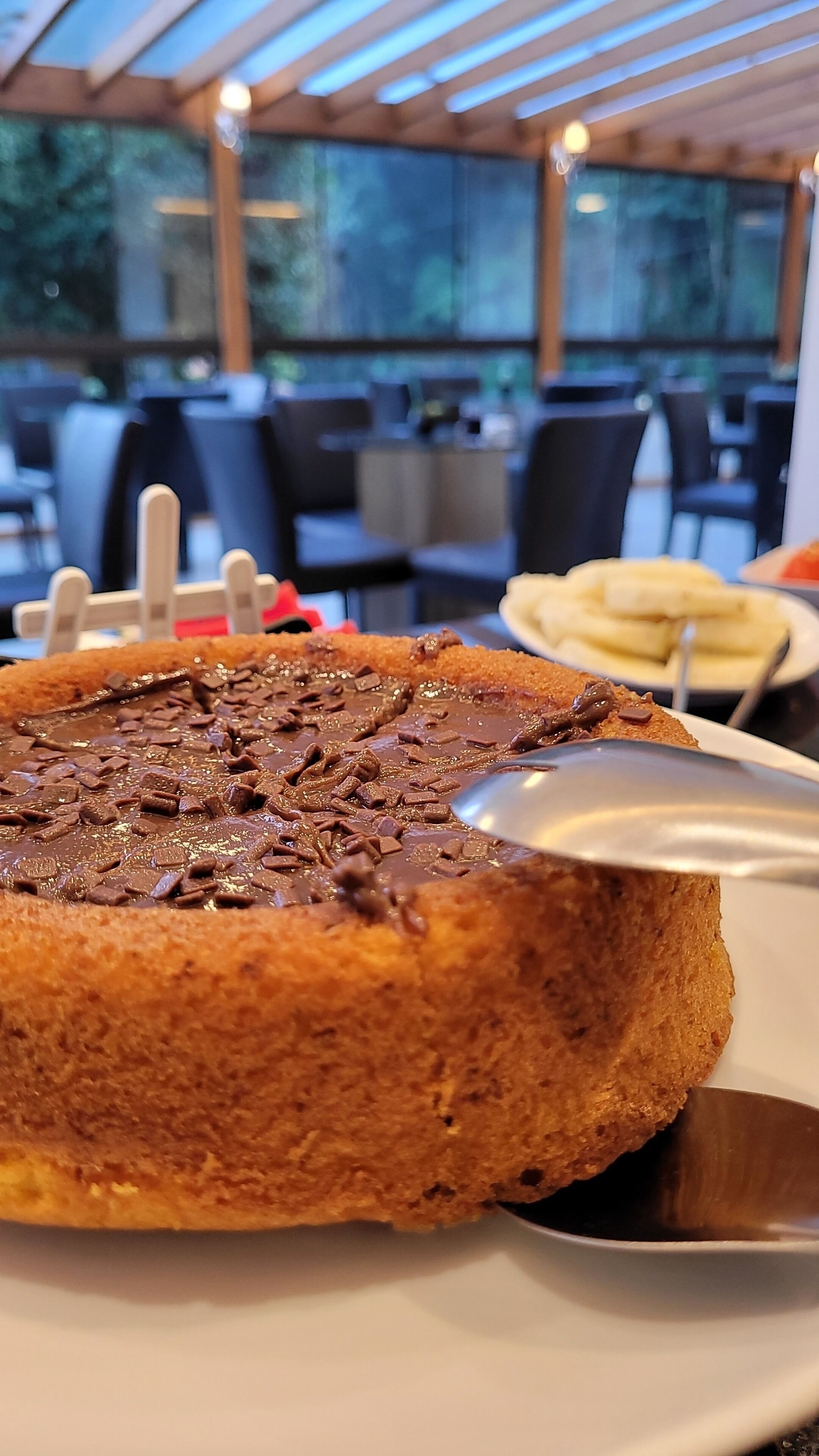 A dessert with chocolate chunks on a plate, with a blurred background of a restaurant setting.