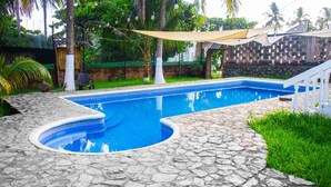 Una piscina con solárium de piedra, rodeada de vegetación y un muro de piedra.