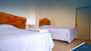Una habitación de hotel con dos camas individuales, un cabecero de madera, una lámpara de noche y una puerta.