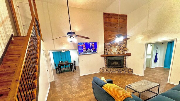 A spacious living area with a stone fireplace, a blue sofa, and a dining area with a table and chairs. - The Simple Dwelling Place (Sulphur)