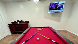 A pool table with a red felt surface, two pool cues, and a cue ball. - The Simple Dwelling Place (Sulphur)