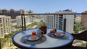 Een balkon tafel met twee borden eten, een mok en een glas sap.
