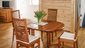 Une table à manger en bois, accompagnée de quatre chaises, un vase avec des fleurs rouges et un lambris en bois.