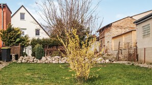 Un quartier résidentiel avec une pelouse verdoyante, un arbre en fleurs et des maisons aux façades en briques et peintes en blanc.