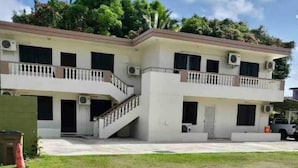 A two-story building with balconies, air conditioning units, and a staircase.
