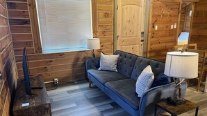 A cozy room with a wooden interior, a sofa, a television, and a door.