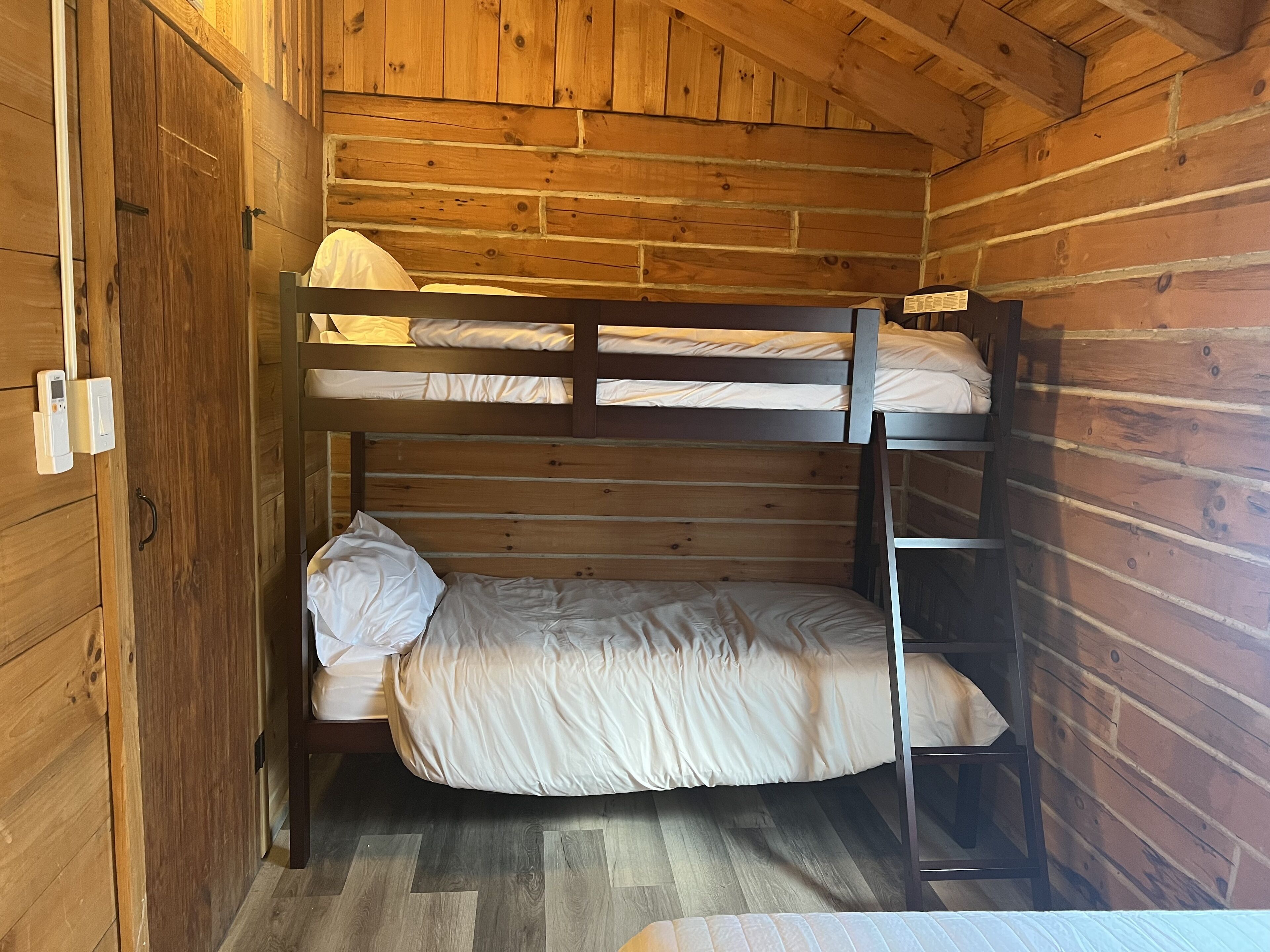 Ein Schlafraum mit Etagenbetten, Holzwänden und Holzboden.