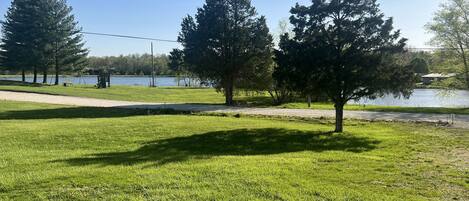 Un parque con césped, árboles, un lago y un sendero.