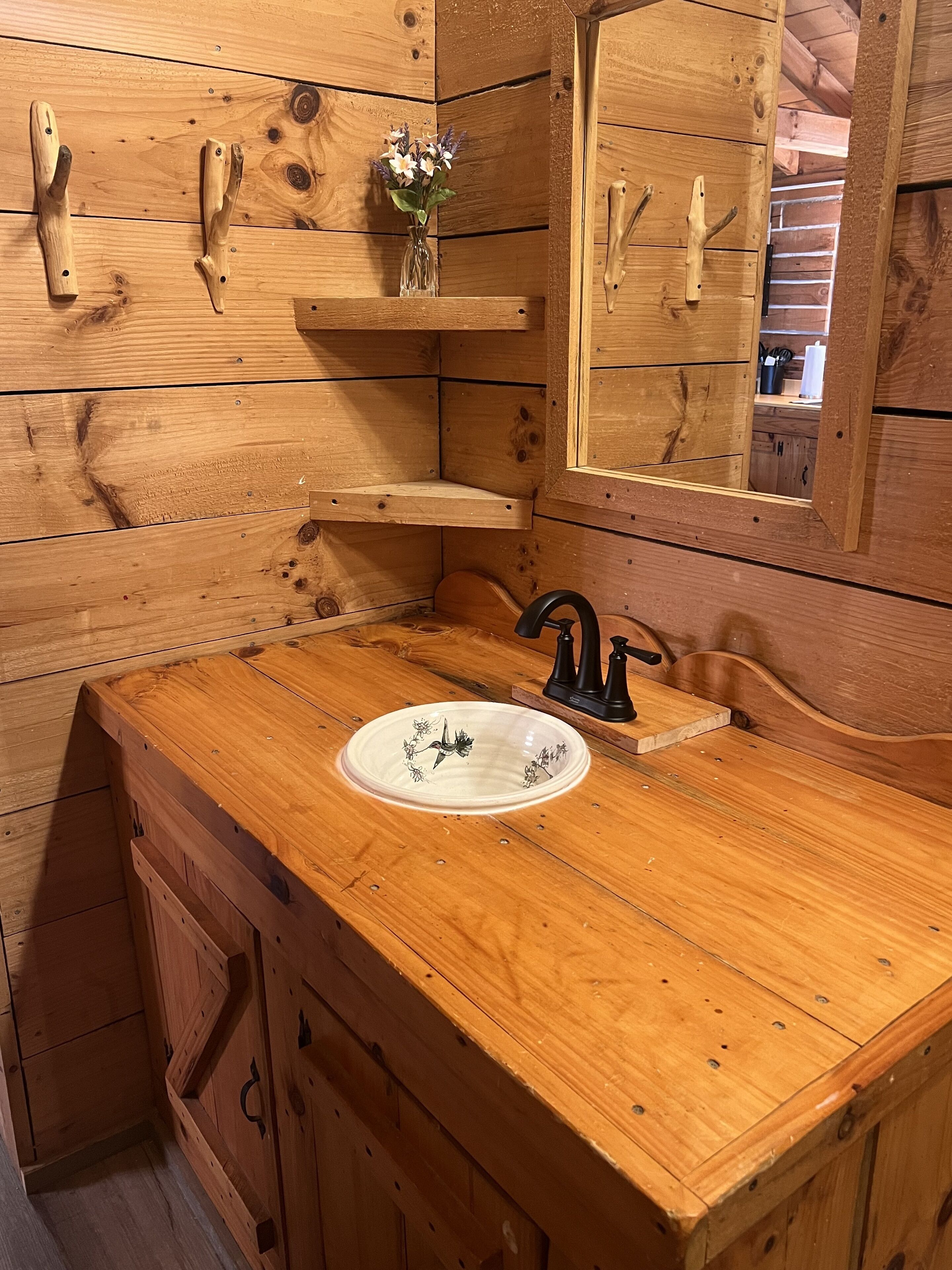 A wooden bathroom vanity with a sink, mirror, and built-in shelves.