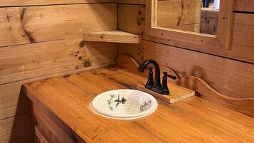 A wooden bathroom vanity with a sink, mirror, and built-in shelves.
