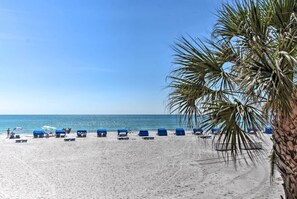 Een strand met wit zand, een helderblauwe lucht en een palmboom.