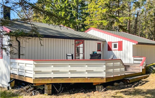 Situated in a wooded area, this cabin offers a front porch with a bench and table for relaxation.
