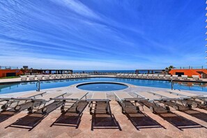 A large, circular swimming pool with lounge chairs and sunbathing areas.