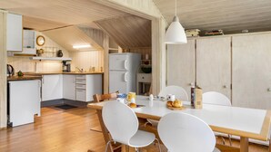 Une cuisine de taille réduite, dotée de meubles en bois, d’un réfrigérateur et d’un coin repas avec une table et des chaises.
