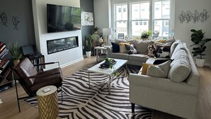 A modern living room with a sofa, coffee table, and a flat-screen TV mounted on the wall.
