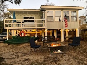 A two-story house with a balcony, a fire pit, outdoor seating, and an American flag. - Riverfront ready for Summer Fun (Moss Point)
