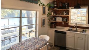 A kitchen with a window, a table with a floral tablecloth, and a sign that reads "RIVER HOUSE". - Riverfront ready for Summer Fun (Moss Point)