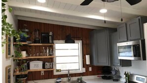 A kitchen with wooden paneling, a built-in microwave, a stove, and a window with blinds. - Riverfront ready for Summer Fun (Moss Point)