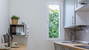 A compact kitchen with a window, a microwave, a sink, and a stove. - El Rincón de Cañadío · Charming Apartment in the Heart of Santander (Santander)
