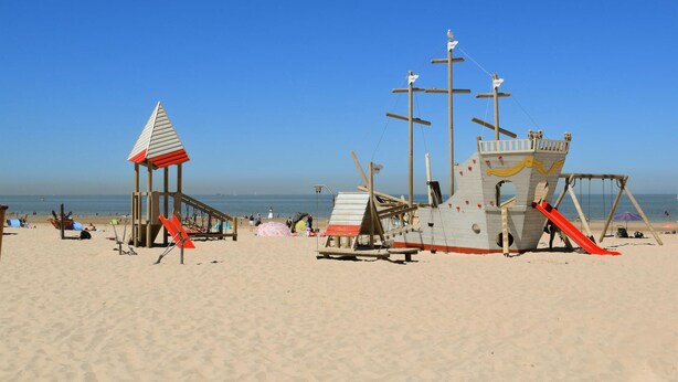 Een strand met een toren voor de strandwacht en een houten speelconstructie.