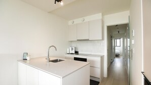 Een moderne keuken met witte kasten, een inbouwkeukeneiland met spoelbak en een vaatwasser.