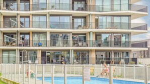 Een hotel met meerdere verdiepingen, balkons, een zwembad en buitenzitplaatsen.