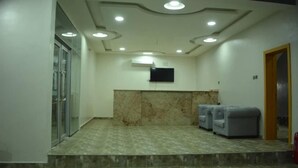 A conference room with a marble floor, a flat-screen TV mounted on the wall, and two gray sofas. - Camas Hotel & Suite Asero Abeokuta (Abeokuta)
