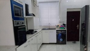Una cocina compacta con gabinetes blancos, estufa, horno y lavadora.