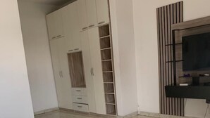 Una habitación amplia con un armario grande, una cama y un televisor montado en la pared.