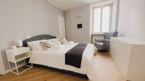 A modern bedroom with a bed, bedside table, chair, and dresser.