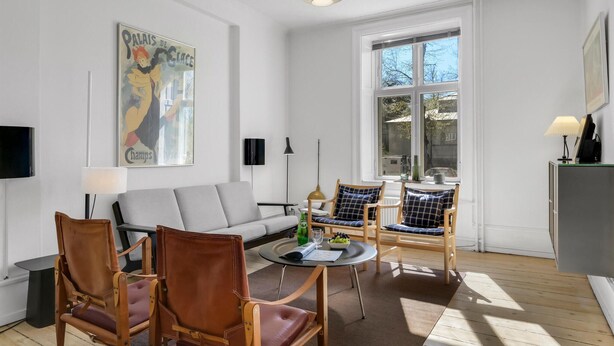 Ein modernes Wohnzimmer mit einer Couch, zwei Sesseln, einem Couchtisch und einem Bild an der Wand.