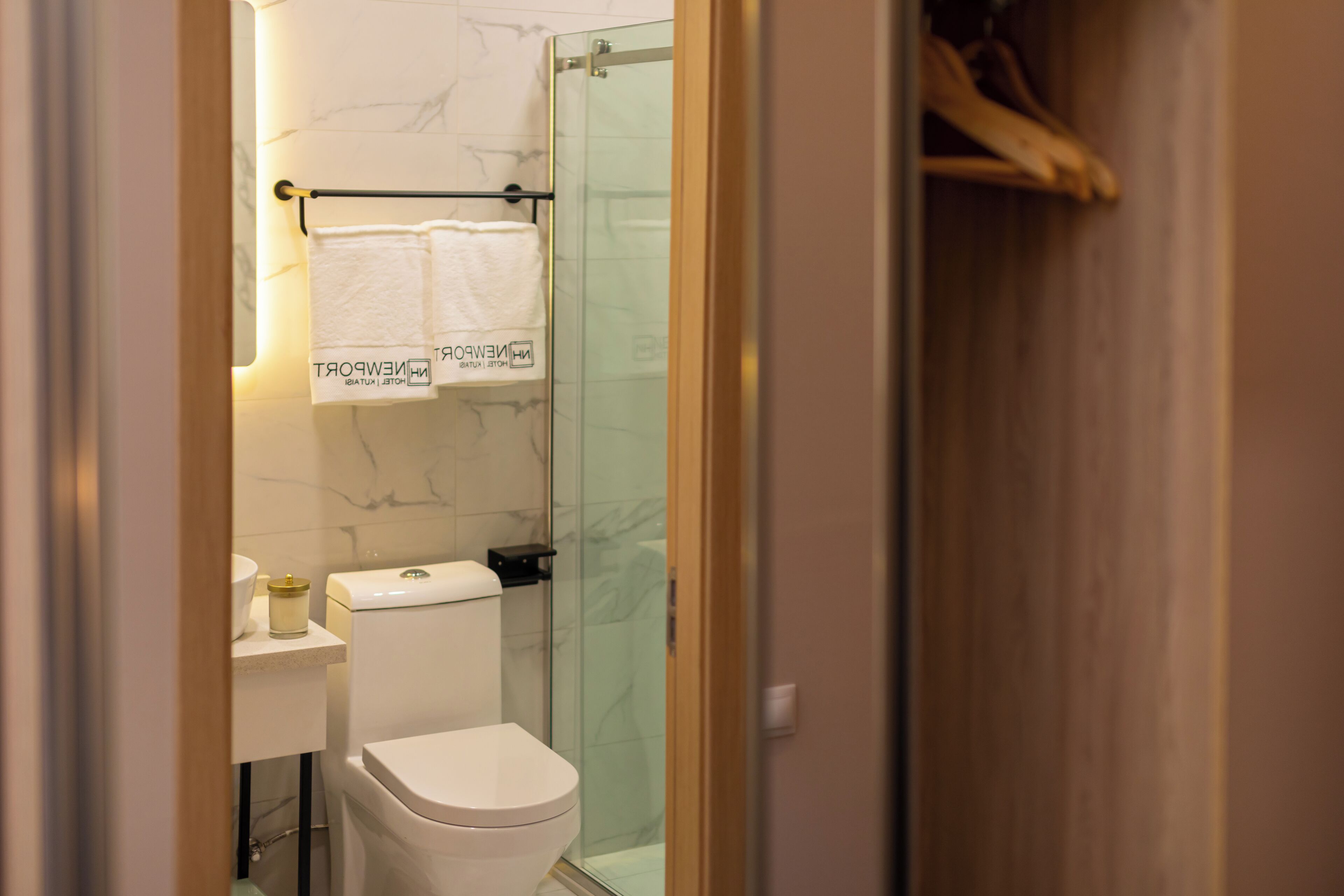 Een moderne badkamer met een douchecabine van glas, een wit toilet en een handdoekrek met een witte handdoek.