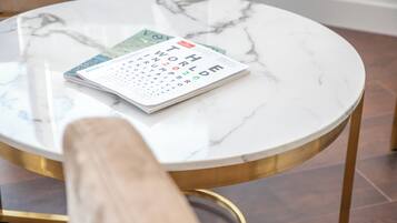 Een ronde tafel met een marmeren blad en gouden poten, waarop een agenda en een tijdschrift liggen.