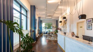 Vestíbulo de hotel con recepción, zona de estar y ventanas amplias.