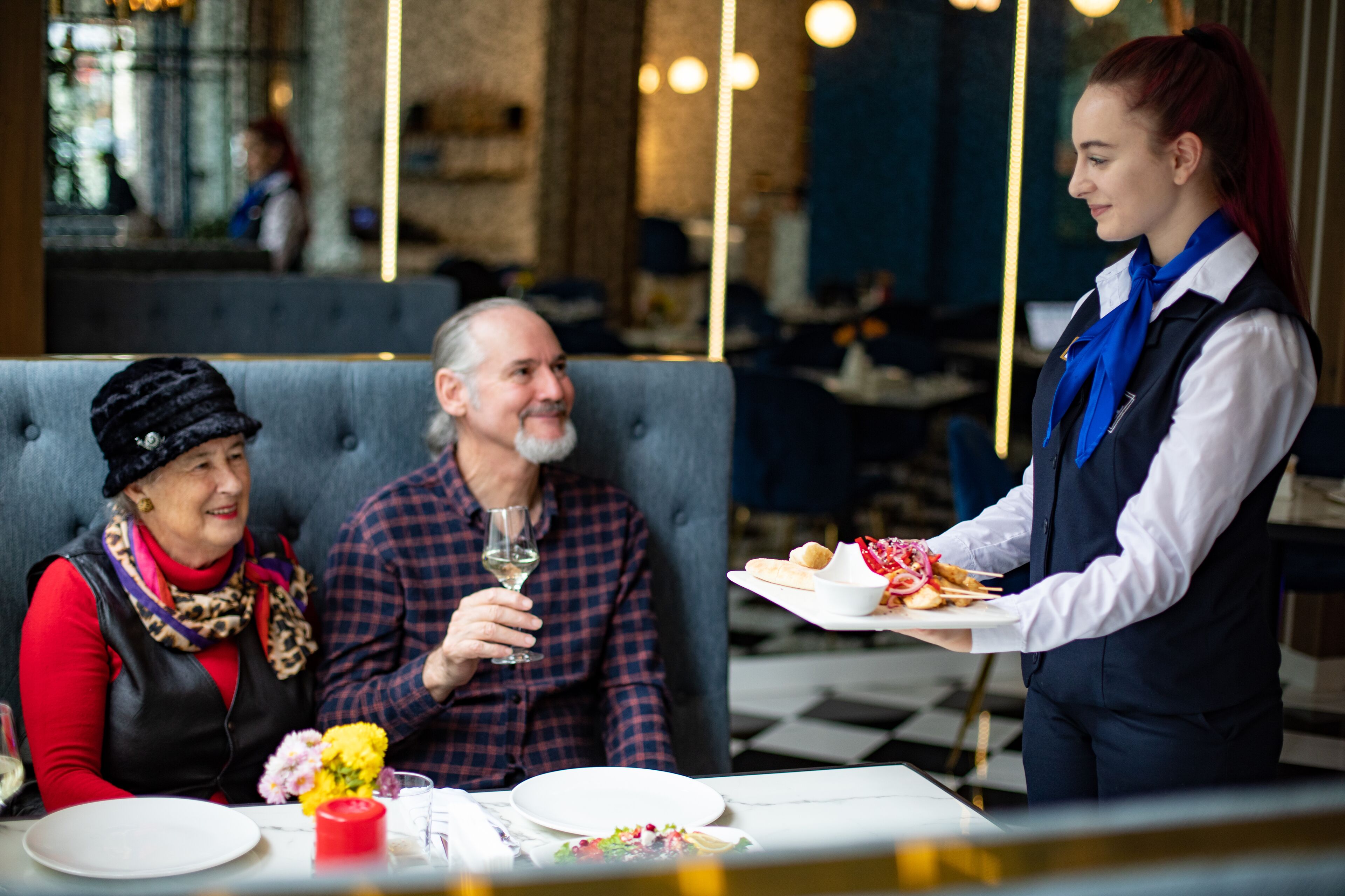 A restaurant setting with a waiter serving food to a table.