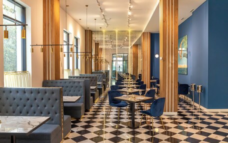 A modern restaurant with checkered flooring, blue and grey seating, and a long counter.