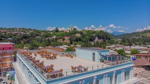 Terraza en la azotea con mobiliario exterior, una piscina y vistas a una colina con edificios y una iglesia.