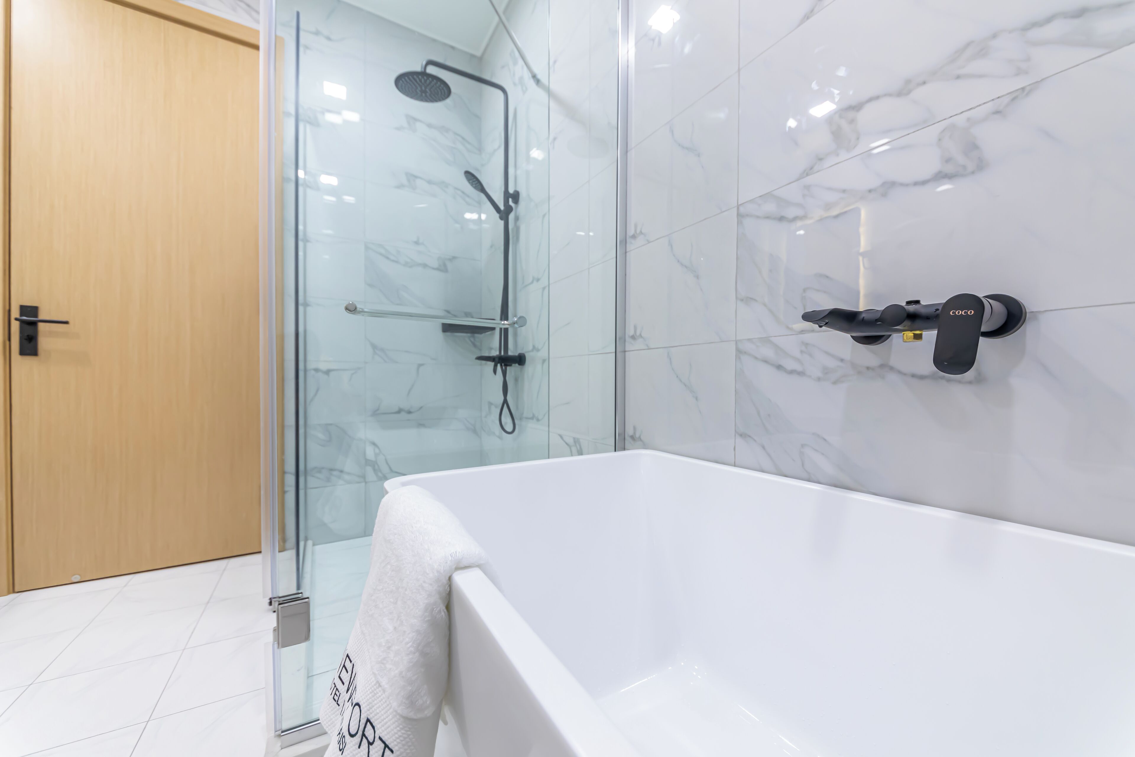 Ein modernes Badezimmer mit Duschkabine aus Glas, einer weißen Badewanne und einer wandmontierten Duschbrause.