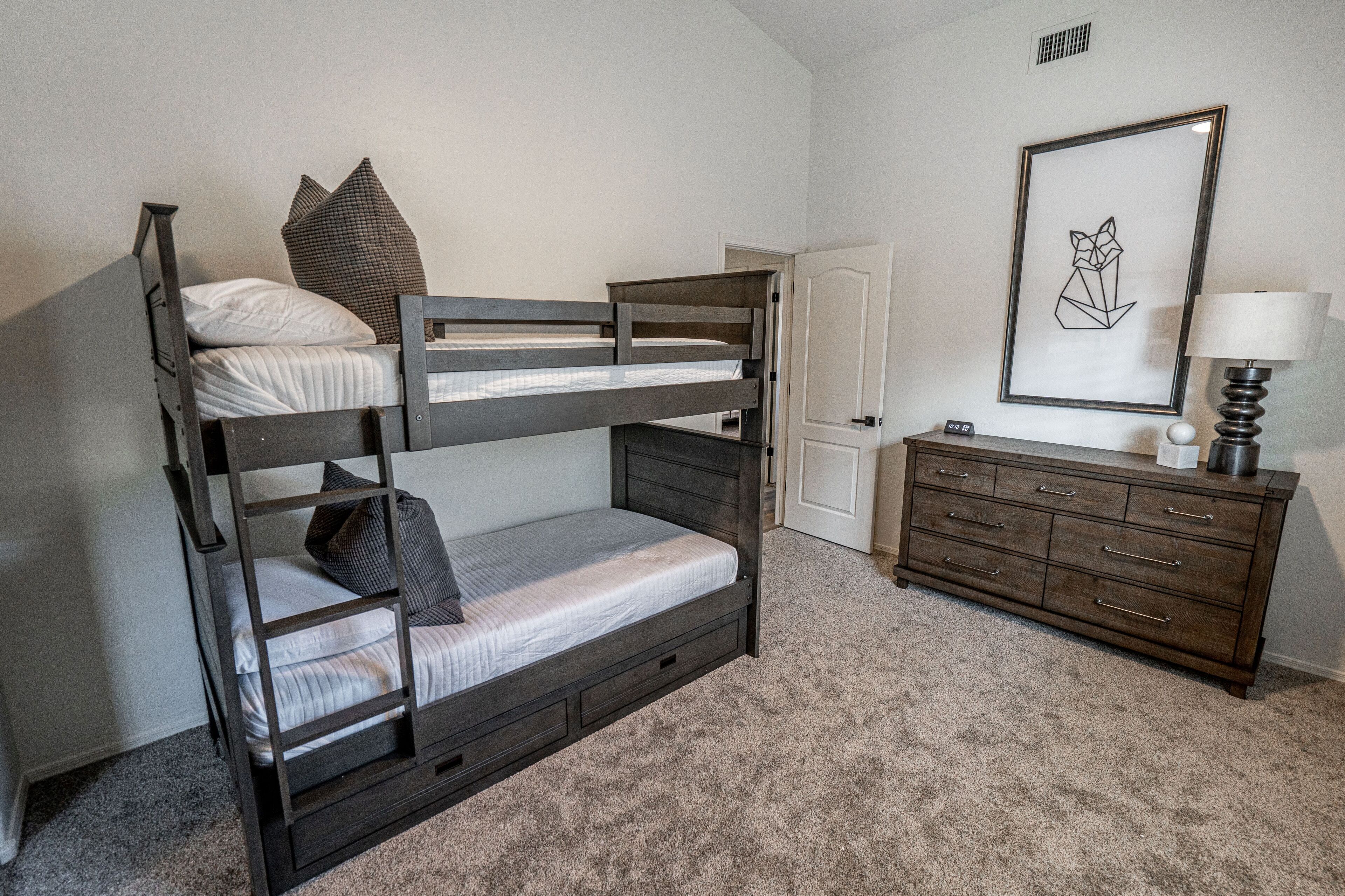 A bunk bed with a dresser and a framed picture on the wall.