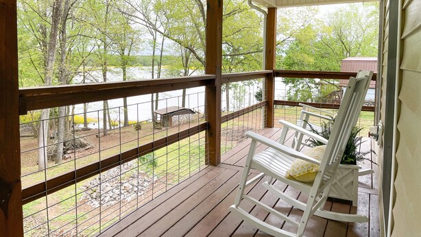 A wooden deck with a railing overlooking a lake, surrounded by trees. - Lake Front, Sunrise, Dock, Kayaks + Game Room (Cadiz)