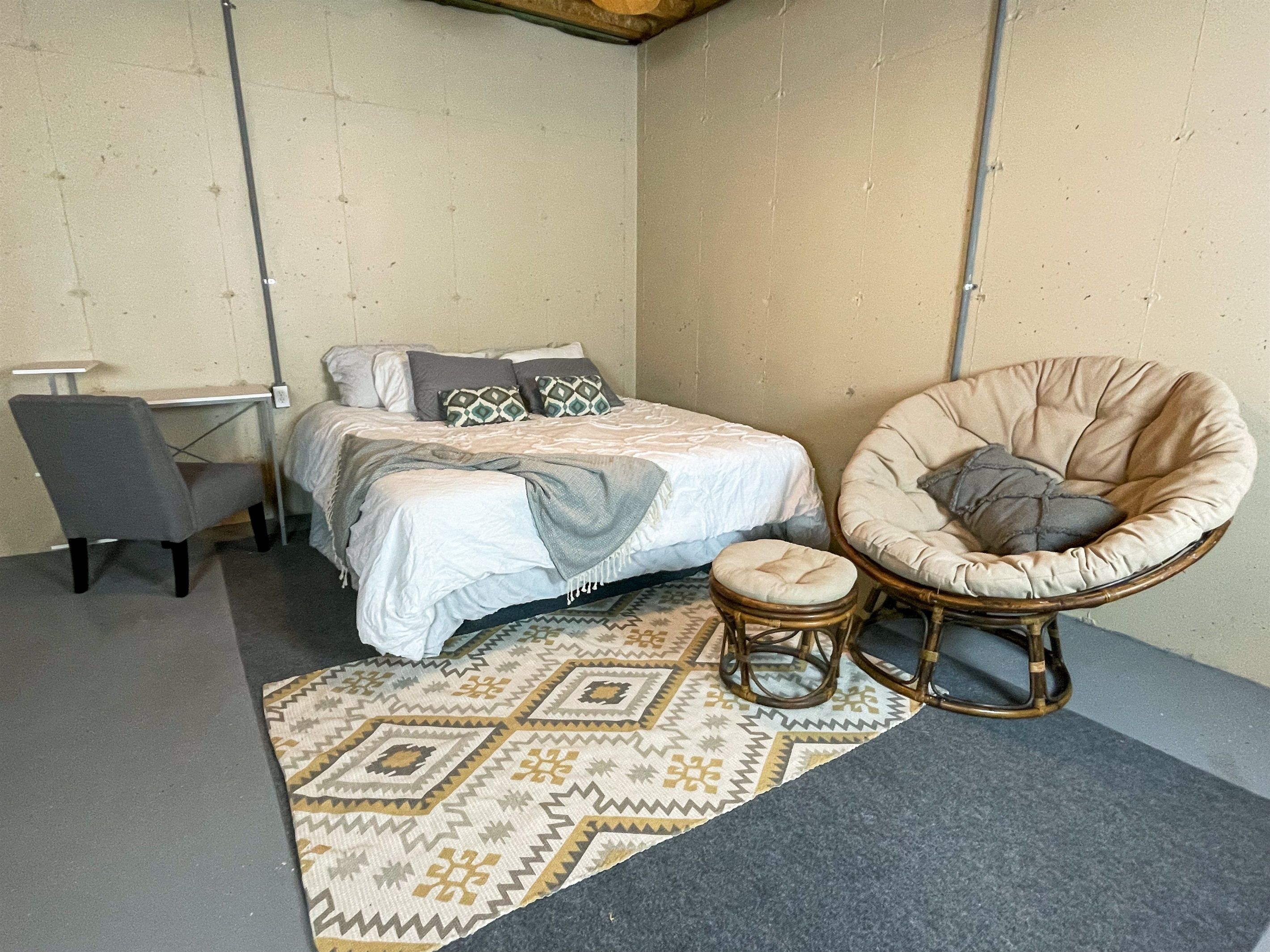 Een knus slaapkamer met een bed, een stoel en een klein tafeltje.